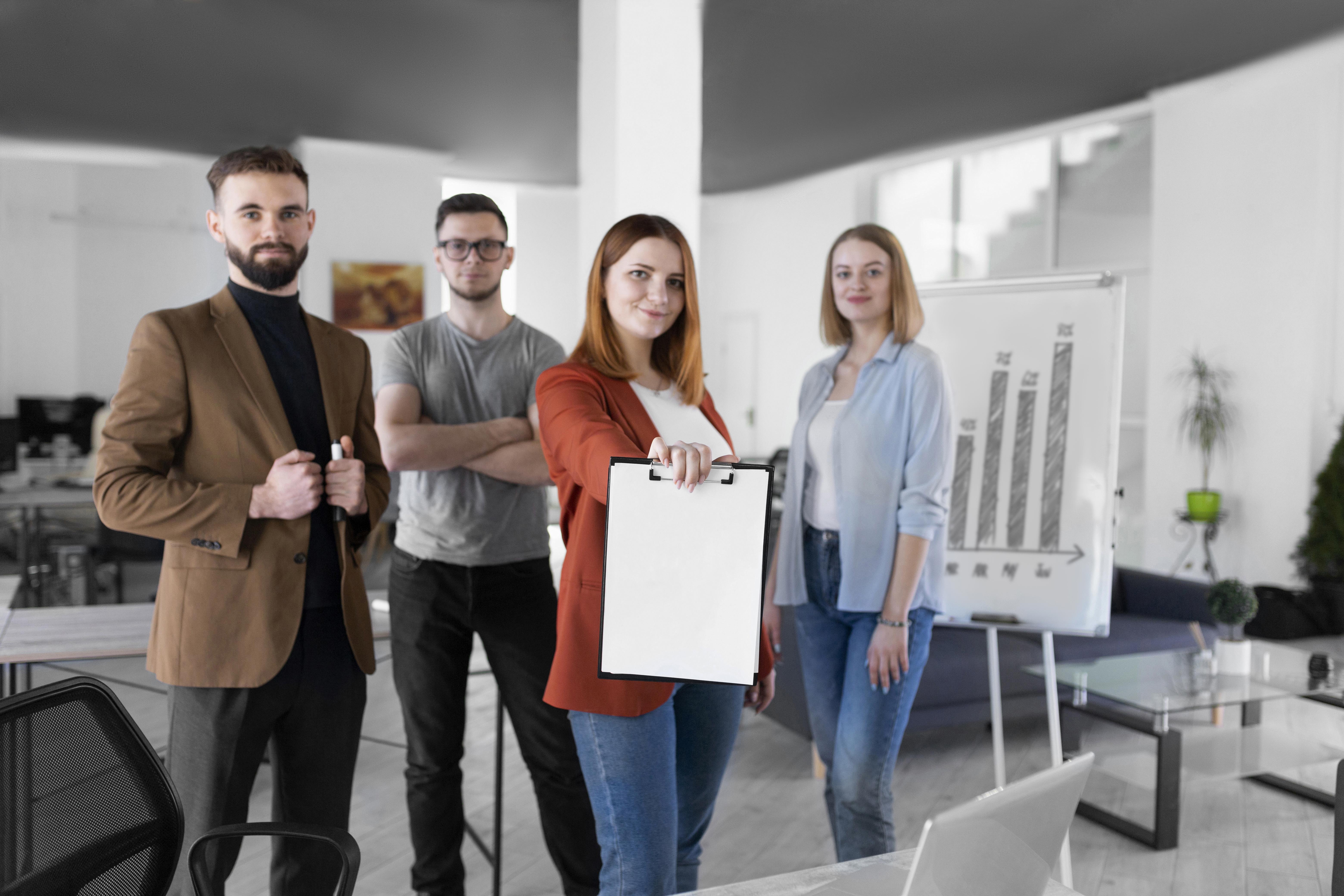 mujer sosteniendo un portapapeles junto sus companeros de trabajo